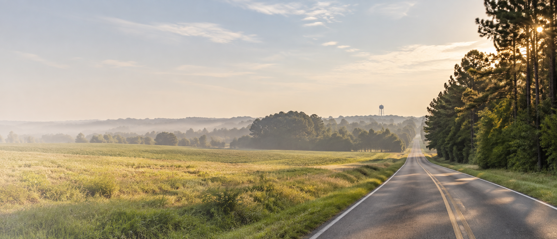 A quiet country road crossing fields outside Trace at sunrise